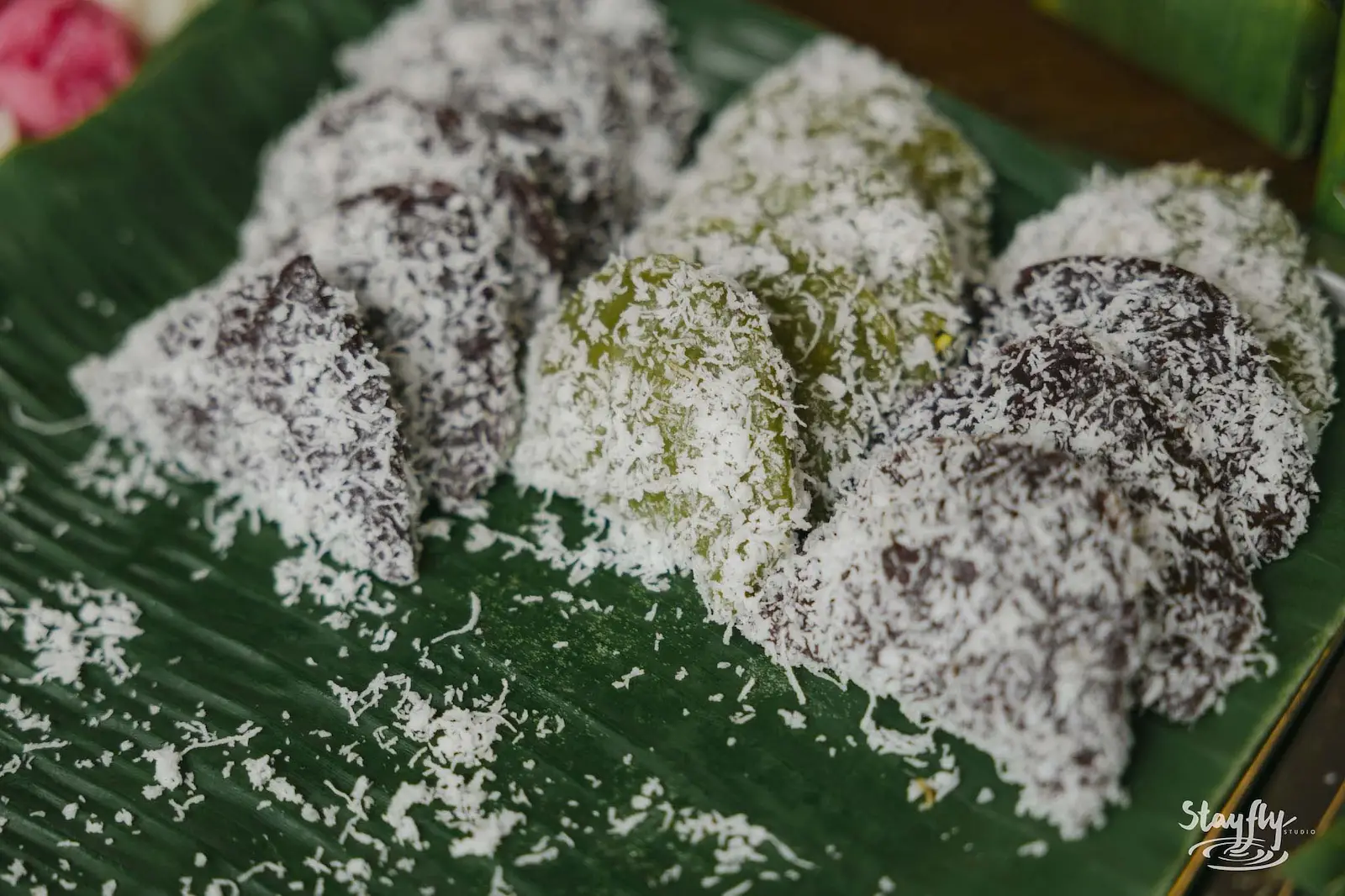 Coconut-coated dessert bites on banana leaf.