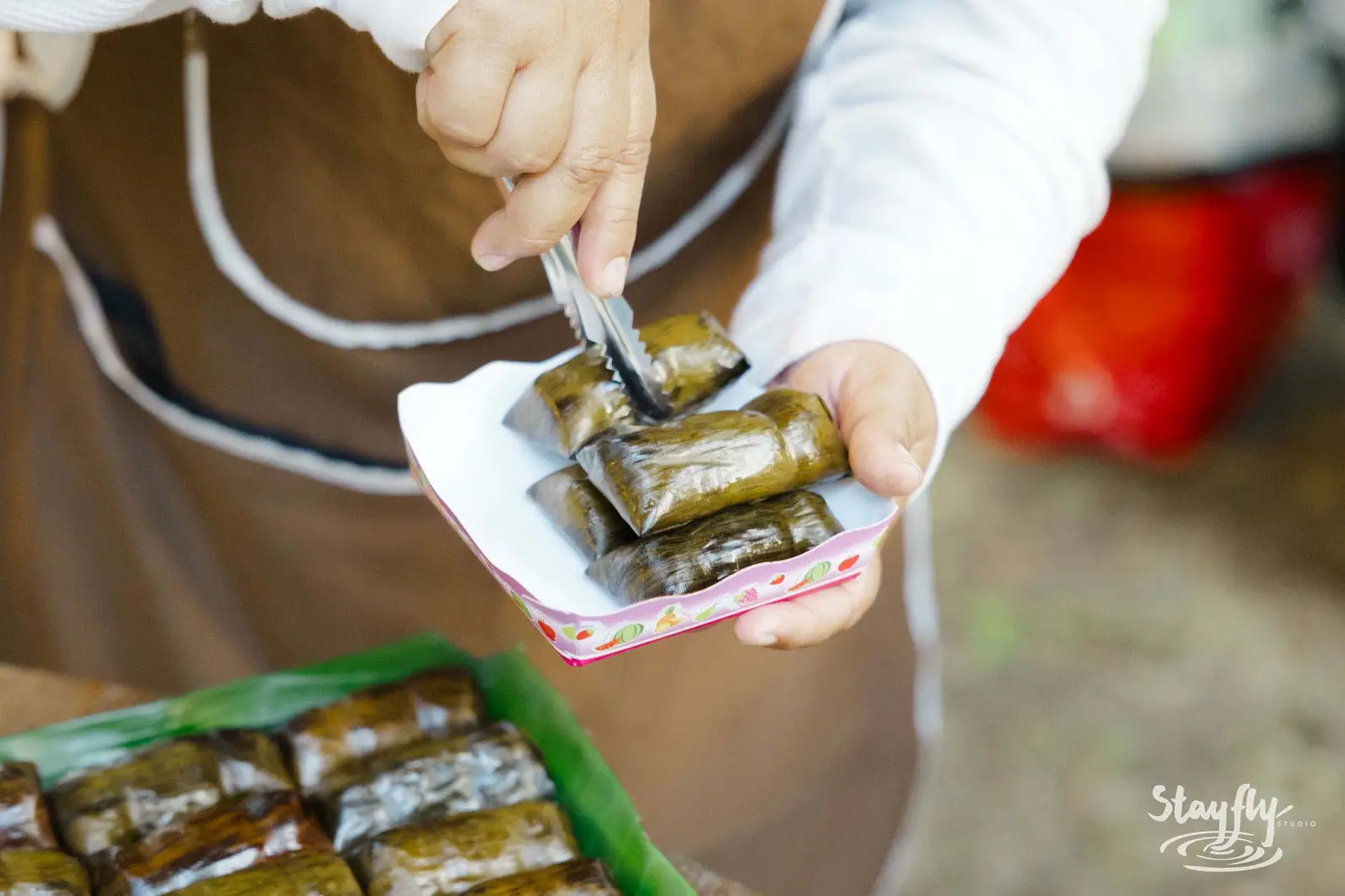 Hands serving wrapped snacks onto plate.
