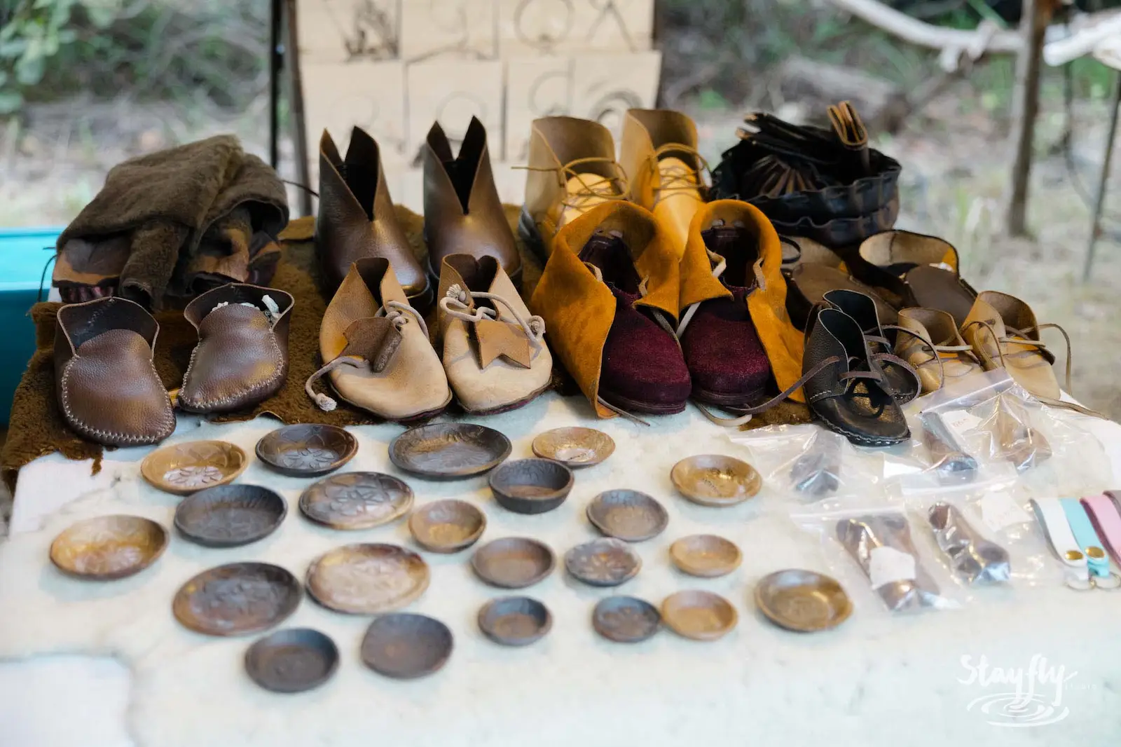 Handmade leather shoes and discs on market table.