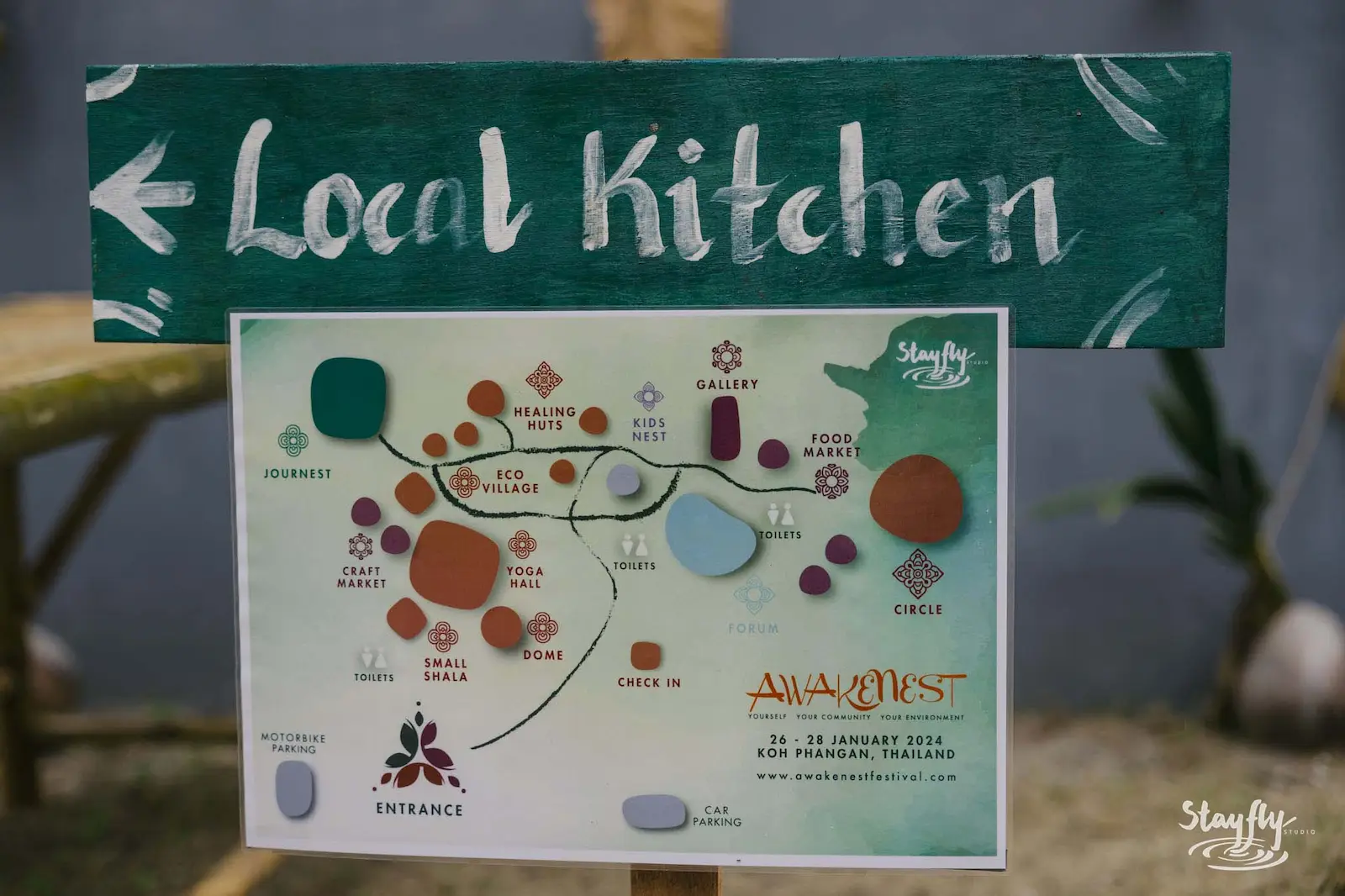 A green Local Kitchen direction sign above a printed 2024 festival map.