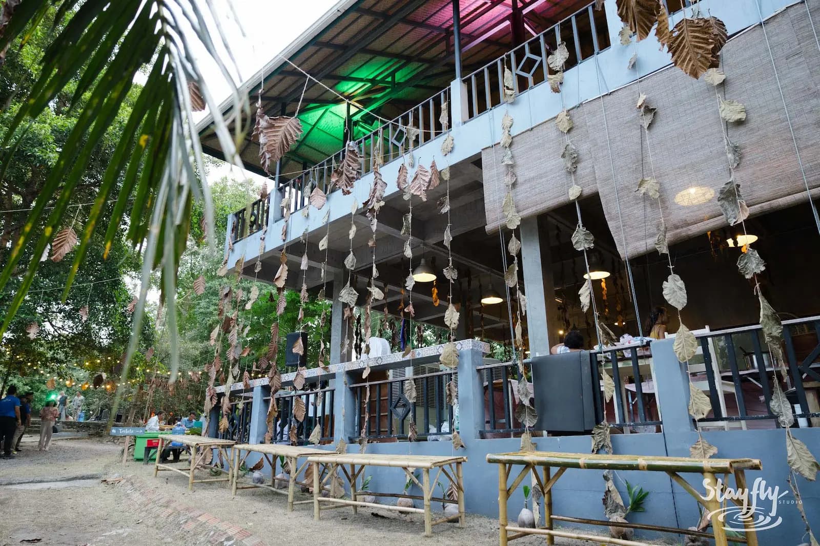 A two-storey open-sided building decorated with hanging leaves and coloured lighting.