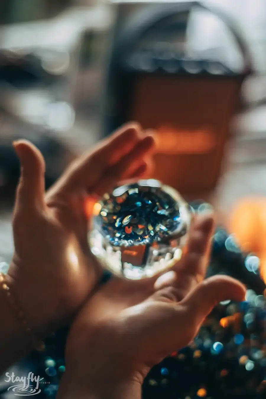 A crystal ball held between finger and thumb with the pavilion reflected in it.